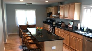 A modern kitchen with a central island, wooden cabinets, and a bar seating area.