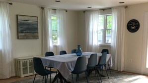 A dining area with a round table, six chairs, and a blue vase.