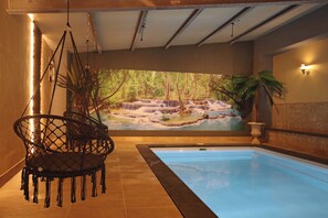 Ein Schwimmbecken mit Wandgemälde eines Wasserfalls, einer Hängematte und einer Wandleuchte.