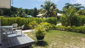 Una terraza con mobiliario exterior, rodeada de exuberante vegetación y palmeras.