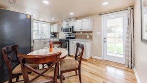 A kitchen with white cabinets, a microwave, and a dining table with chairs. - Near Downtown Waxhaw Mellow Yellow Suite A  (Waxhaw)