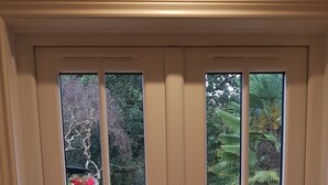 A white double door with a view of a garden and a pathway.