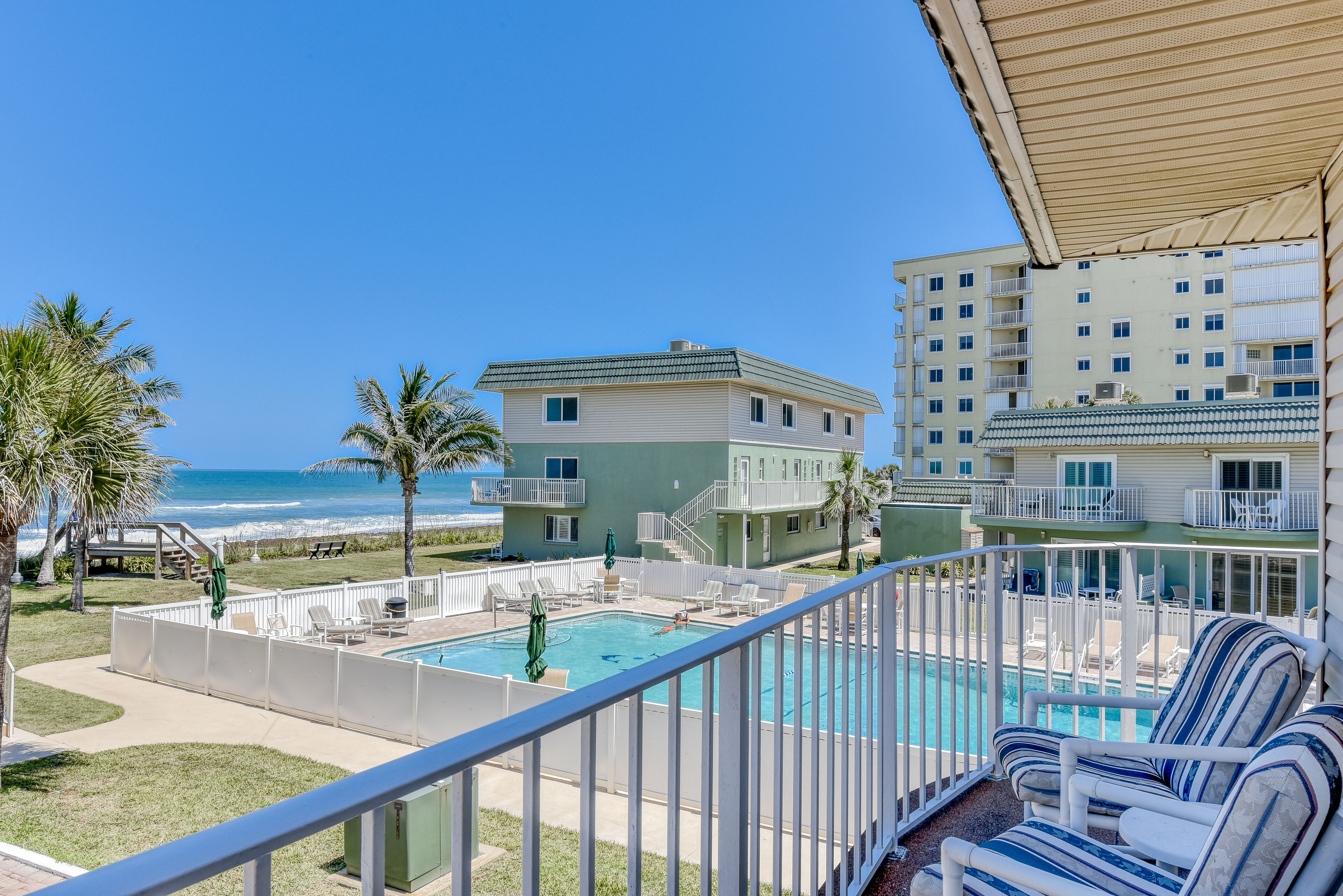 A pool area with lounge chairs and a view of the beach.
