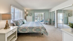 A bedroom with a bed, a nightstand, a dresser, a chair, and a large mirror. - Direct Ocean View- Heated Pool- New Wrap Around Balcony- (Indialantic)