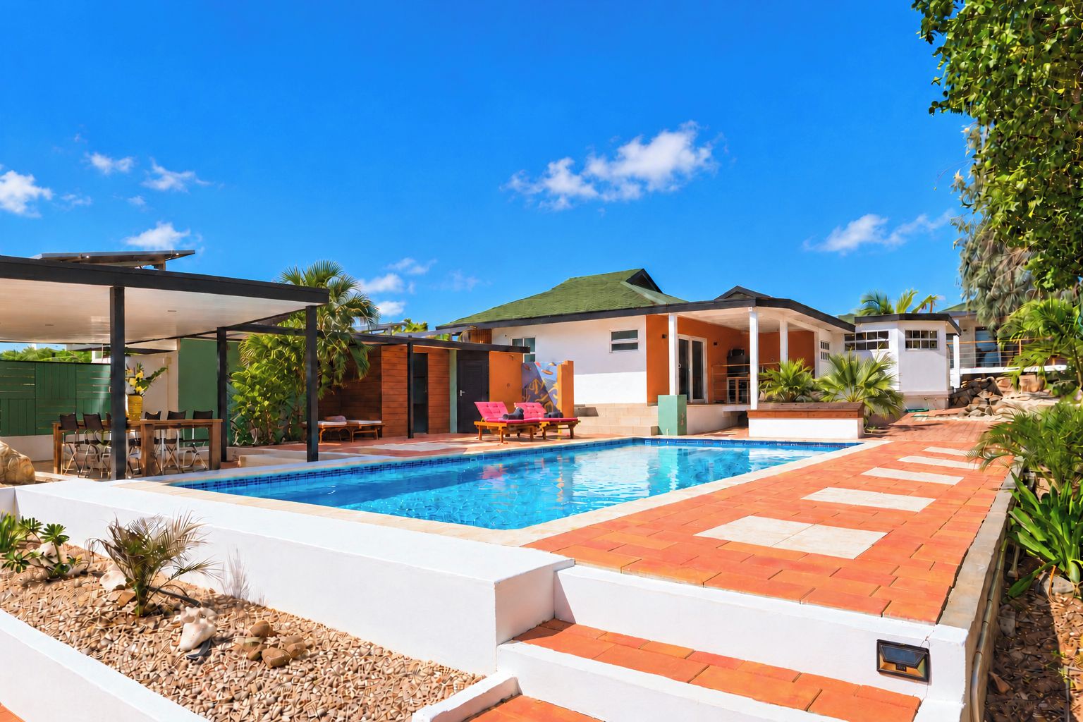 Una piscina con una veranda coperta, una casa a due piani e un giardino curato.
