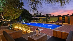 A swimming pool with lounge chairs and a wooden deck.