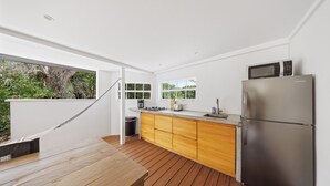 A modern kitchen with wooden cabinets, a stainless steel refrigerator, and a hanging hammock.