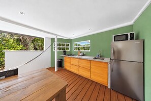 A modern kitchen with a wooden table, a stainless steel refrigerator, and a view of greenery outside. - Unique experience in the nature of Aruba #2 (Paradera)
