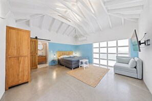 A modern bedroom with a bed, a sofa, a large window, and a wooden wardrobe. - Unique experience in the nature of Aruba #2 (Paradera)