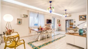 Un salon moderne avec un coin repas, des murs blancs et un lustre.