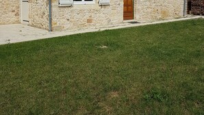 Ein Haus aus Stein mit Ziegeldach, einer Holztür und einem kleinen Fenster mit Fensterläden.