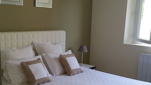 Ein Schlafzimmer mit einem großen Bett, einem Kopfteil und zwei Nachttischen mit Lampen.