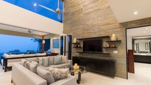 A modern living room with a large sofa, a glass coffee table, and a fireplace.