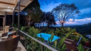 Un balcone con mobili in vimini, una piscina e vista sul paesaggio circostante.