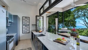 Una cucina moderna con una grande isola, elettrodomestici in acciaio inossidabile e vista sull'oceano.