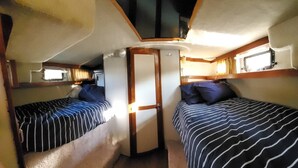 A compact RV interior with two striped beds, a small kitchenette, and a door leading to an external area.