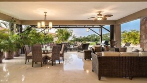 A spacious indoor area with a dining table, chairs, and a sofa. There are potted plants and a ceiling fan. - Luxury Ocean View Ground Floor, Premier Golf and Beach Clubs (Punta Mita)