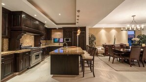 A spacious kitchen with dark wood cabinets, granite countertops, and a central island. - Luxury Ocean View Ground Floor, Premier Golf and Beach Clubs (Punta Mita)