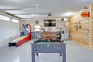 A room with a foosball table, a bar area, and a mounted television.