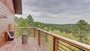 En träaltan med ett metallräcke, en stol och en soptunna.