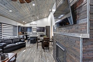A modern kitchen with dark cabinetry, a central island, and a built-in TV. - Game room, fully paved roads, WiFi and luxury finishes (Lead)