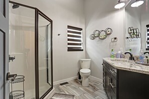 A bathroom with a glass shower enclosure, a toilet, a vanity with a sink, and a mirror. - Game room, fully paved roads, WiFi and luxury finishes (Lead)