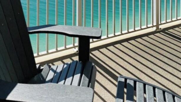 A wooden deck with a metal railing overlooking a clear blue sea. - Penthouse! Great Rates! Quiet, Clean, Well Maintained Building. Book Now. (Panama City Beach)