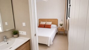 A bedroom with a bed, bedside table, lamp, and a potted plant.