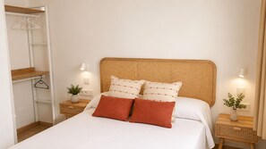 A bedroom with a bed, two bedside tables, a bedside lamp, a closet, and a wall-mounted shelf.