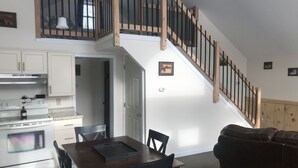 Une cuisine moderne avec des meubles blancs, une table à manger en bois et un escalier doté de rampes en bois.