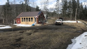 A rustic cabin with a metal roof, a small porch, and a wooden deck.