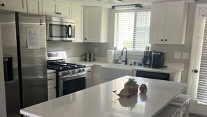 Una cocina moderna con armarios blancos, electrodomésticos de acero inoxidable y una isla central con taburetes de bar.