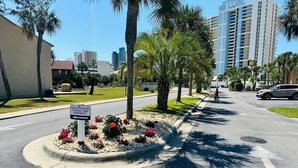 Una calle con acera, palmeras y un cartel que indica el uso peatonal de la acera.