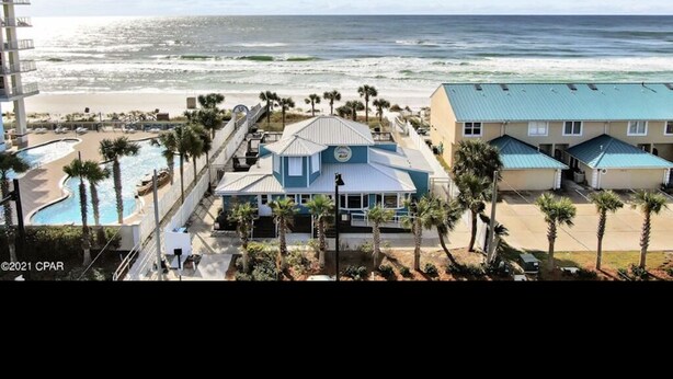 Un resort con piscina, vista a la playa y un edificio con techo azul.