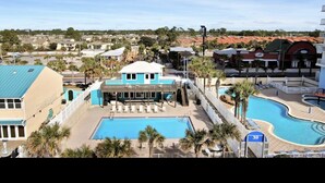 Un resort con un amplio espacio de piscina, una torre de salvavidas y un edificio con techo azul.