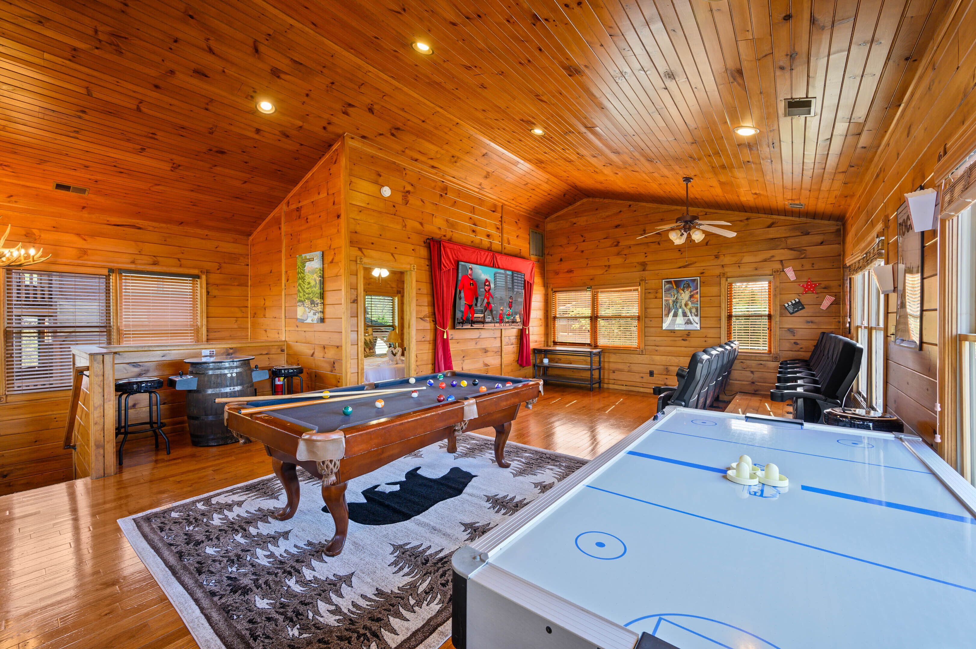 A wooden cabin interior with a pool table, a foosball table, and a bar area.