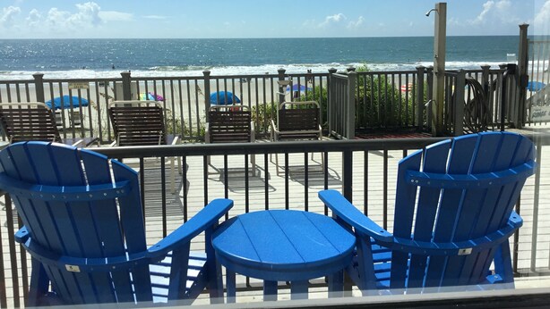 A deck with blue chairs and umbrellas overlooking the ocean. - Ground floor Condo - No need for elevators - Steps away to the beach and pool. (Murrells Inlet)