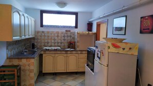 Una cocina compacta con ventana, un refrigerador decorado con motivos de frutas y un rebozo de azulejos.