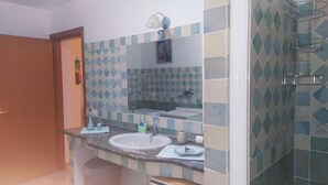 Un baño con lavamanos, espejo y paredes de azulejos.