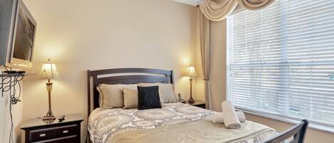 A neatly arranged bedroom with a bed, two bedside tables, a lamp, and a window with blinds.