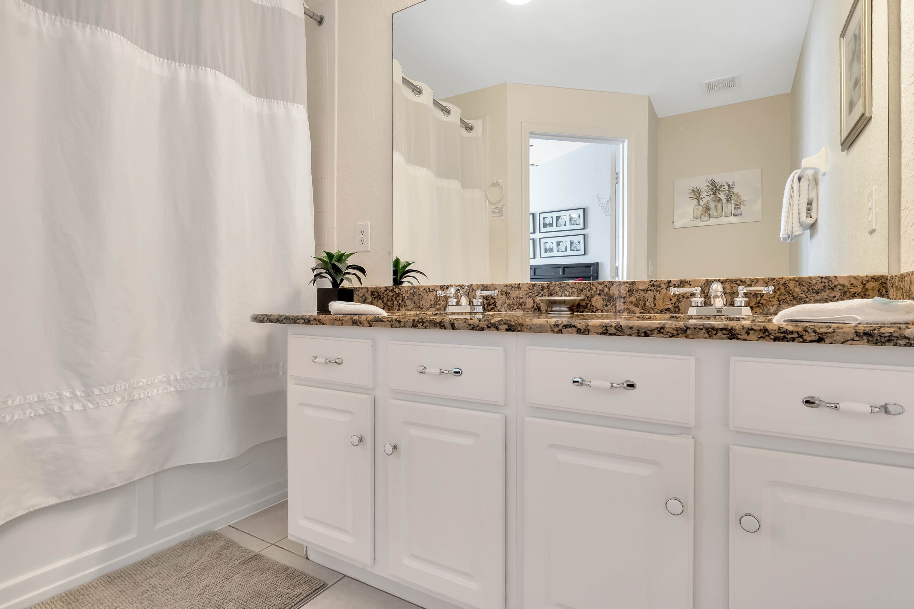 A bathroom with a white vanity, a large mirror, and a shower curtain.
