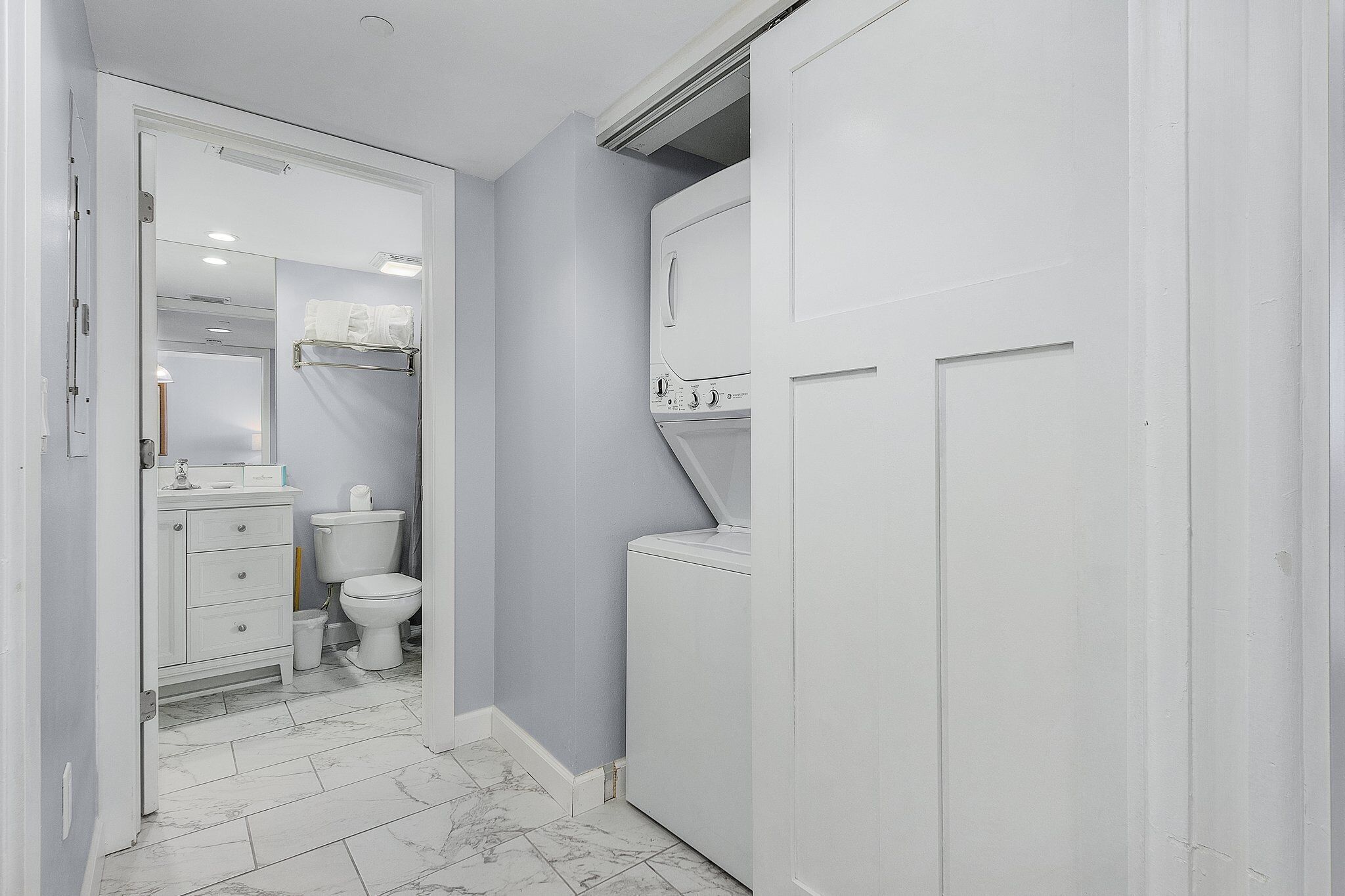 A compact bathroom with a toilet, sink, and a built-in washing machine.