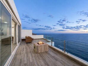 A modern outdoor terrace with a fire feature, seating, and a view of the sea. - VIP Luxury - Villa Lands End - Bartender, Chef, & Maid included (Cabo San Lucas)