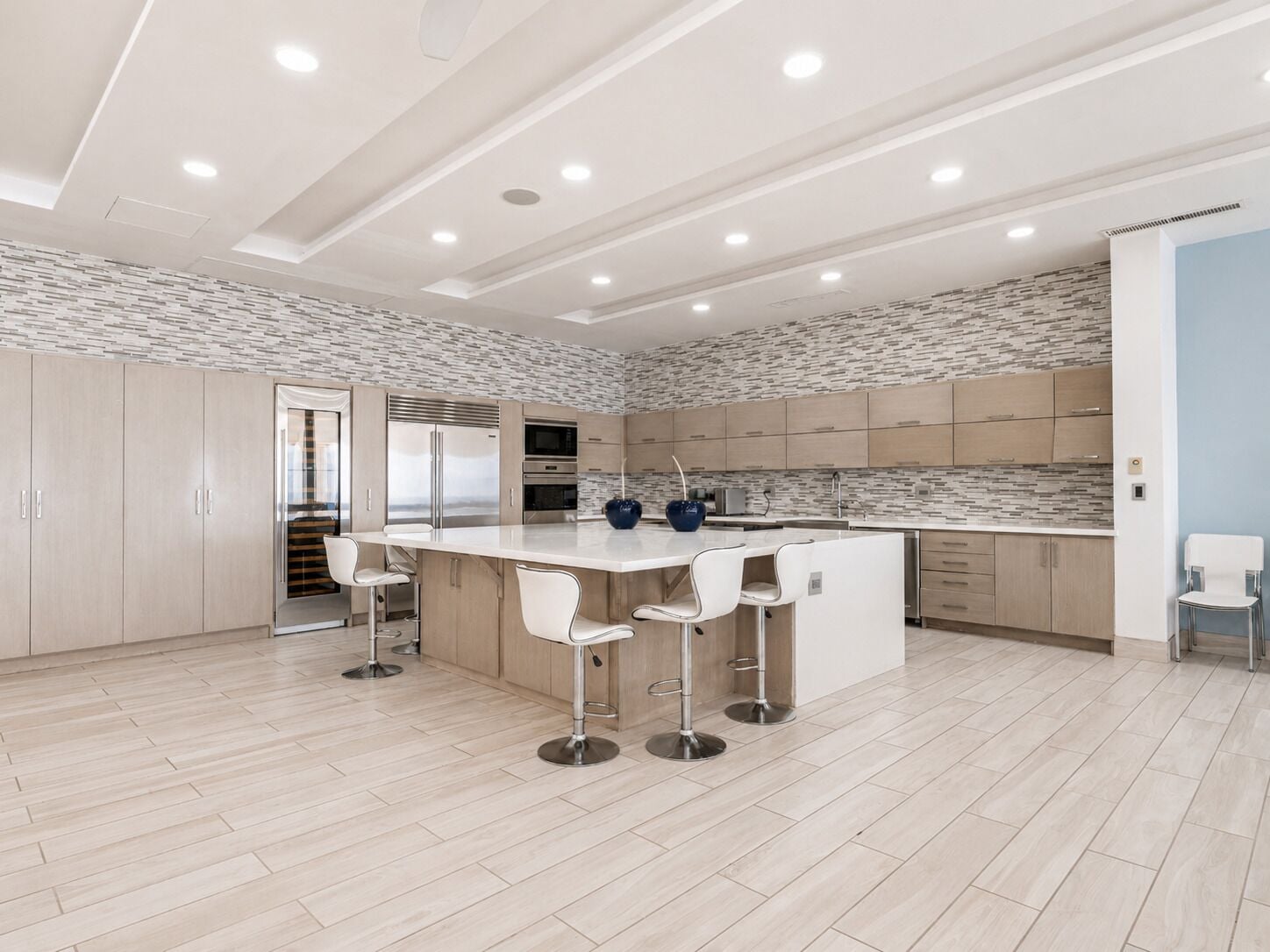 A modern kitchen with a central island, bar stools, and a patterned backsplash.