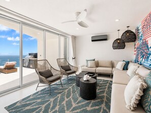 A modern living room with a large glass door leading to a balcony, a ceiling fan, a sofa, and a coffee table.