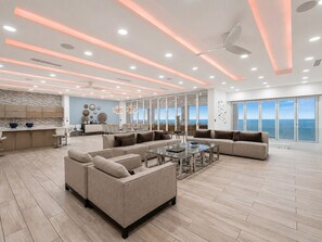 A spacious living area with a large sofa, a coffee table, and a view of the ocean through large windows.