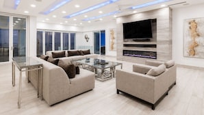 Una sala de estar moderna con un sofá modular, una mesa de centro de vidrio, un televisor de pantalla plana y una chimenea.