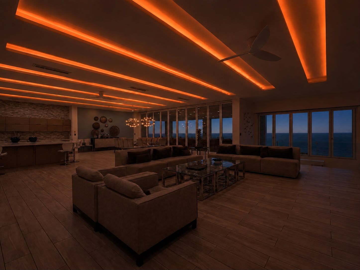 A modern living room with a large sofa, a coffee table, and a view of the ocean through large windows.