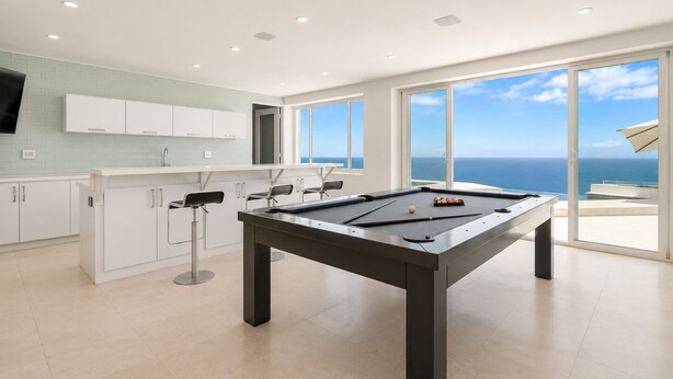 Una mesa de billar moderna en una habitación luminosa con vistas al océano.
