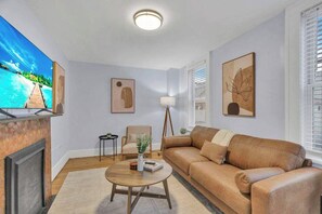 Un salon avec un canapé, une table basse, un téléviseur et des œuvres d’art accrochées aux murs.
